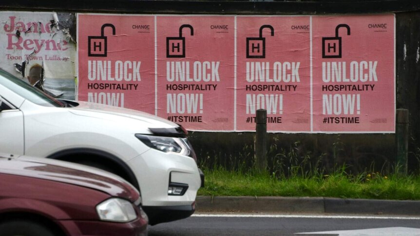 A poster by the side of a road says 'Unlock hospitality now.'