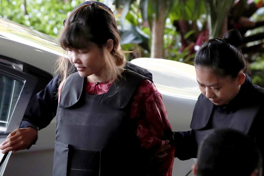 Vietnamese Doan Thi Huong looks down as she is escorted by two police officers.