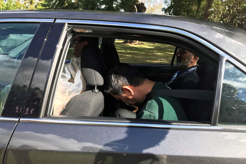 Zhen Jie Zhang in the back of a car with a Queensland police officer