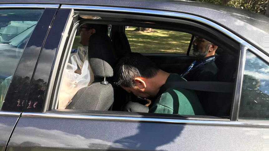 Zhen Jie Zhang in the back of a car with a Queensland police officer