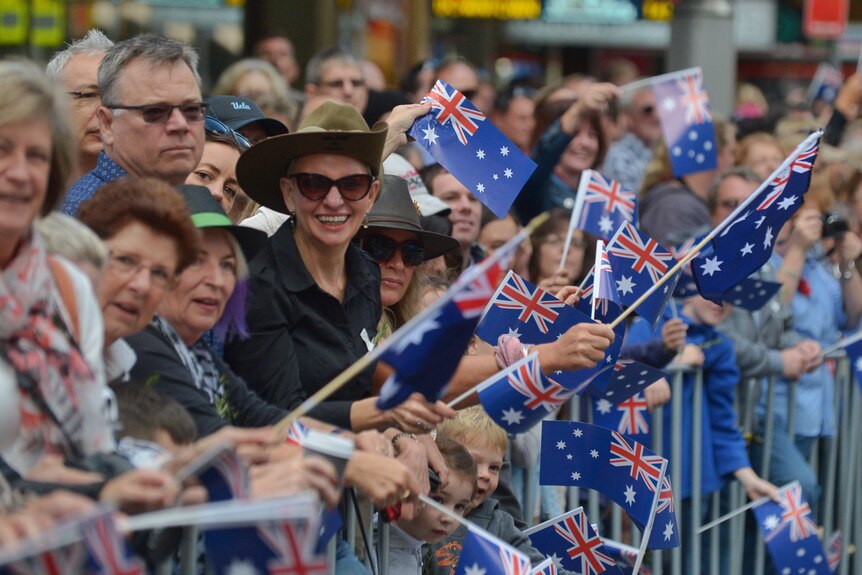 Spectators wave flags at the Anzac Day march