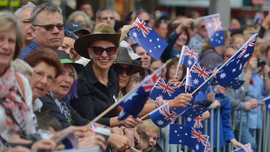 Spectators wave flags at the Anzac Day march