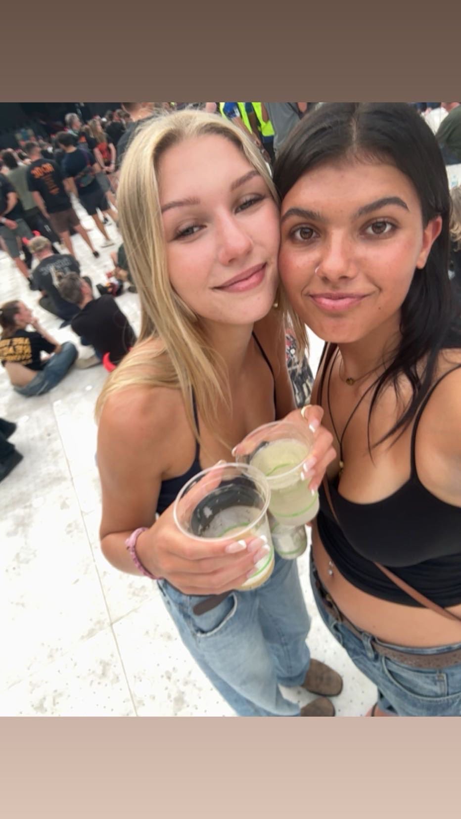 Dos mujeres jóvenes con las cabezas juntas en un concierto.