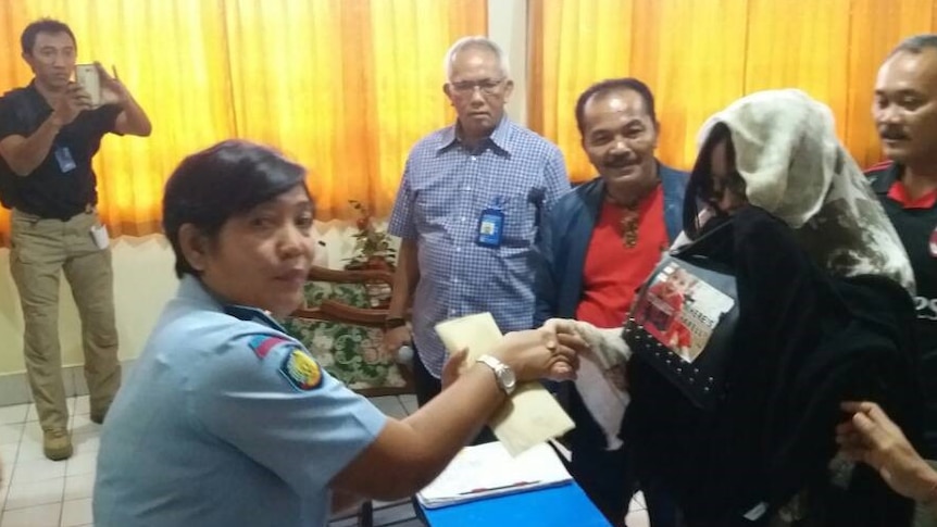 Schapelle Corby at parole office shaking hands with an officer.