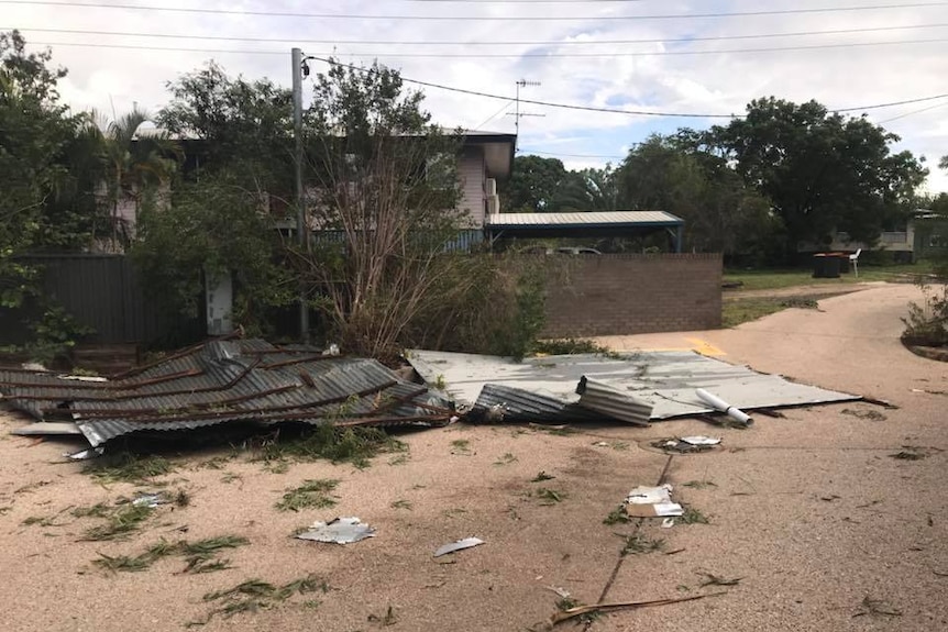 Collapsed metal sheeting and damage to a home caused by a storm.