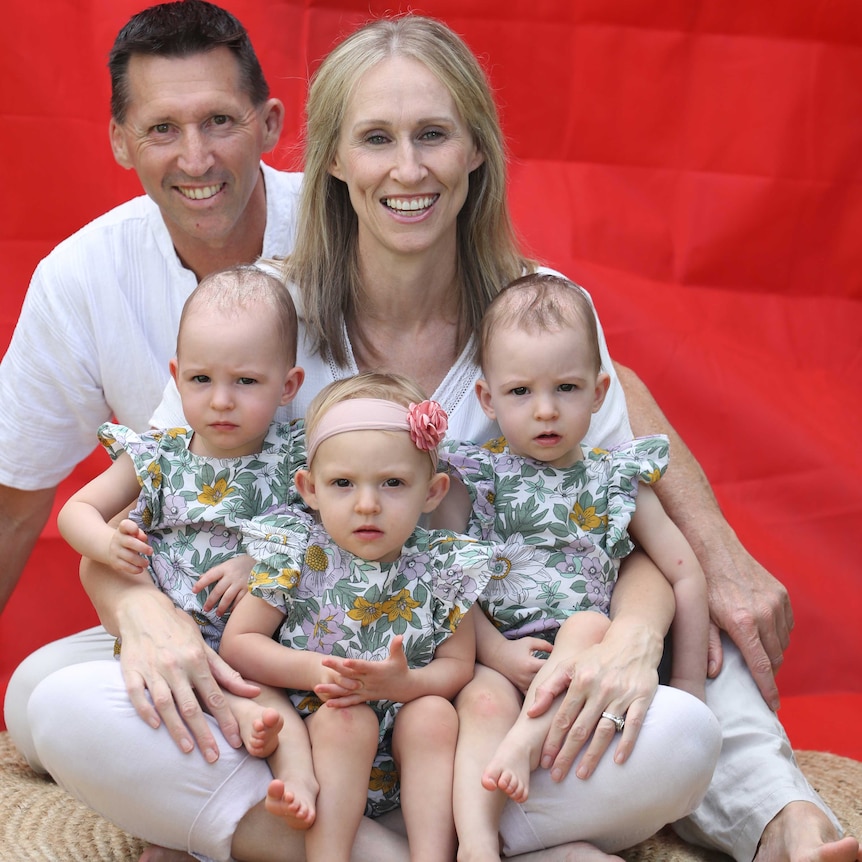 Peter and Leonie Fitzgerald smiling with triplets Liliana, Charlotte and Isabella