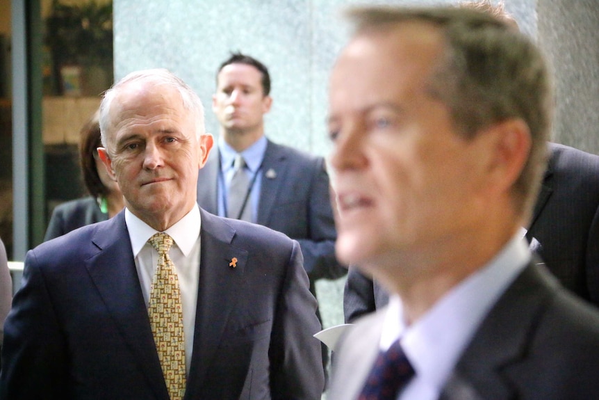 Prime Minister Malcolm Turnbull watches Opposition Leader Bill Shorten speak.