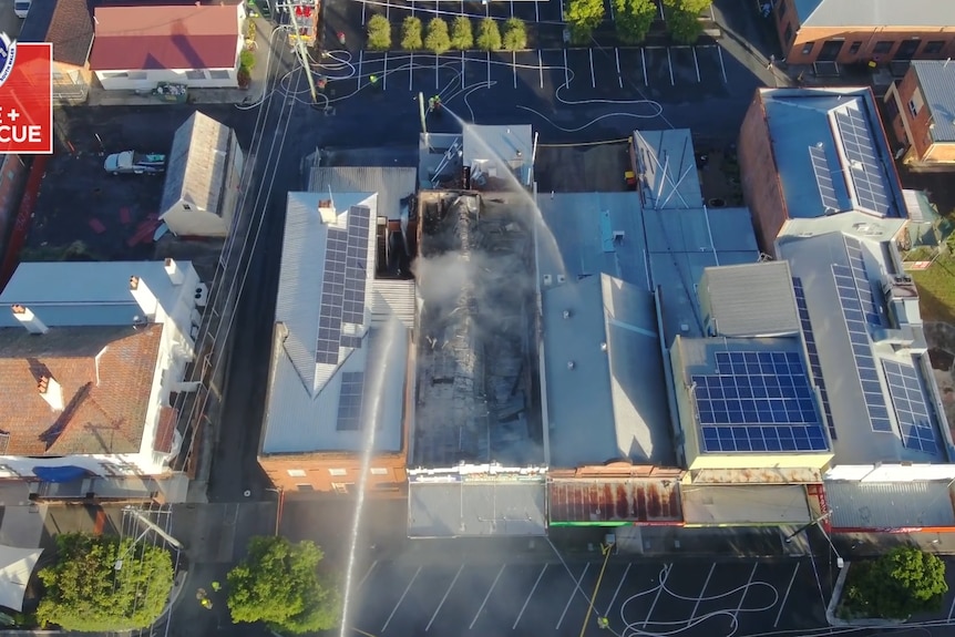 An aerial view of a building badly damaged by fire and its roof caved in.