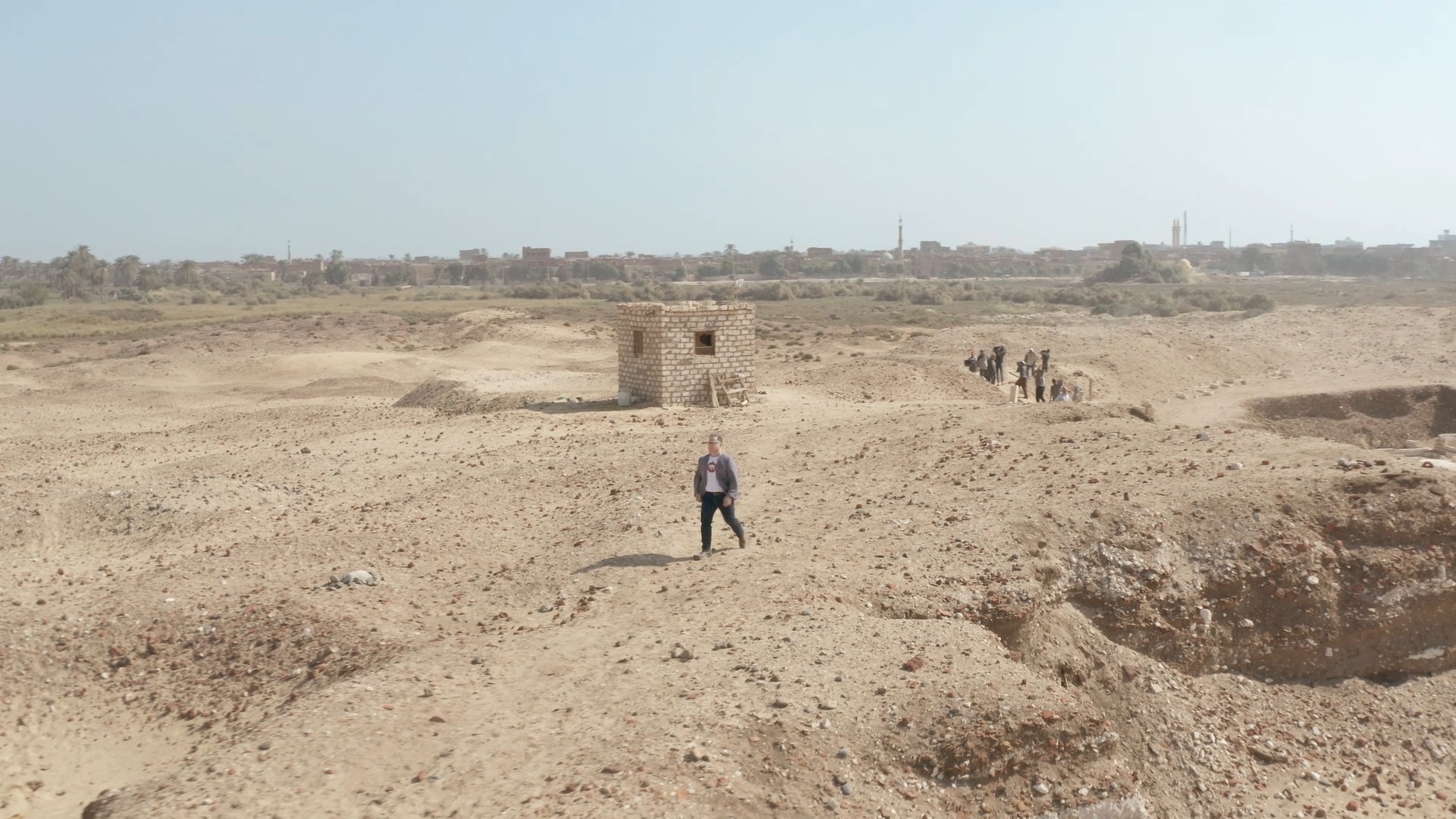 Um homem caminhando em uma escavação arqueológica no deserto.