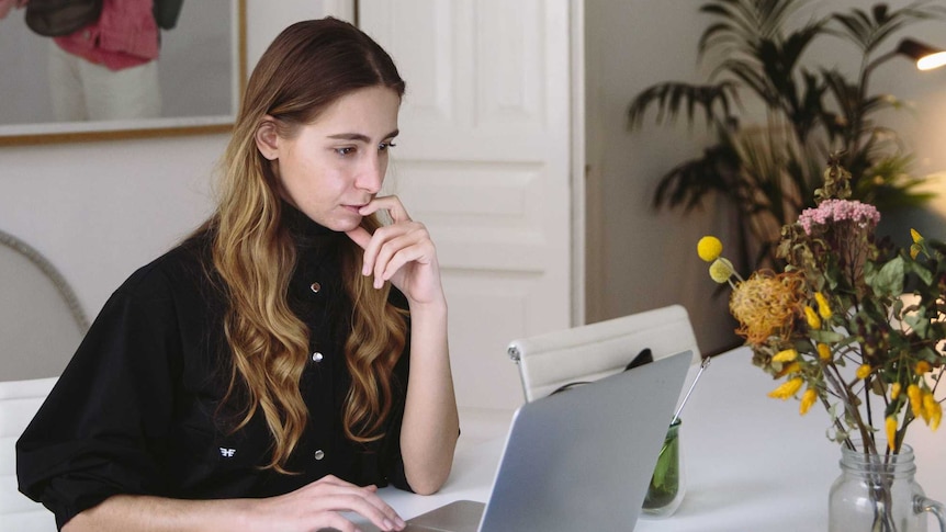 Woman looking at her computer, in a story about a quick guide to cervical screening test results (formerly pap smear).