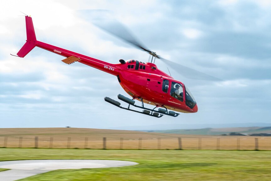 A red helicopter taking off