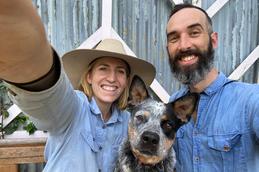 A man and a woman take a selfie holding their dog