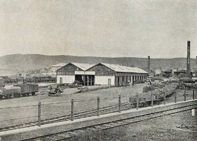 Black and white photo of an old goods shed with a railway line next to it 
