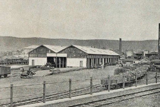Black and white photo of an old goods shed with a railway line next to it 