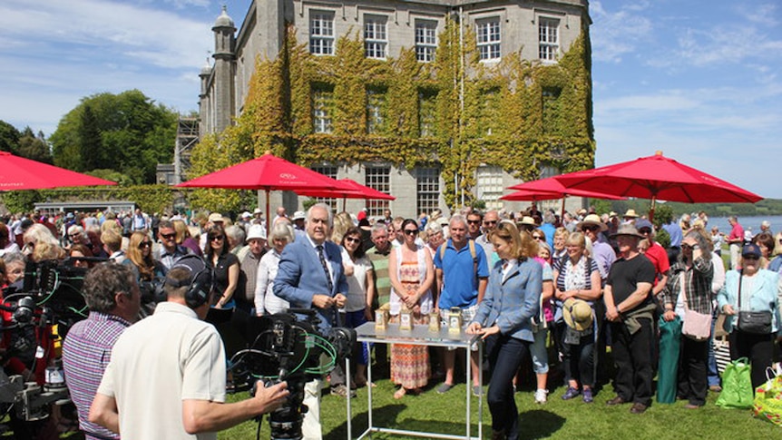 People standing around old antique clocks in a garden