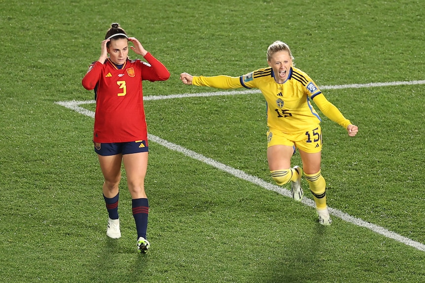 La sueca Rebecca Blomqvist pasa junto a una jugadora española con los brazos extendidos tras marcar un gol durante la Copa Mundial Femenina.