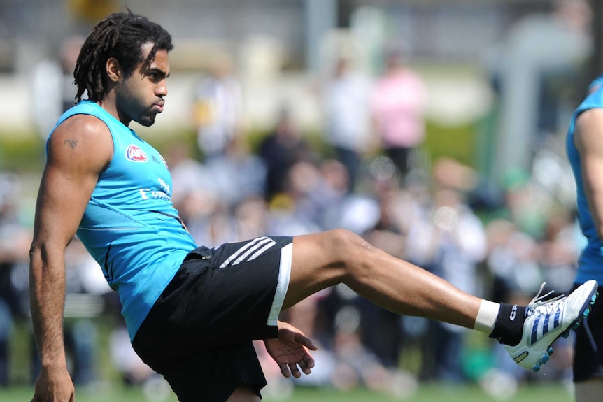 An AFL player kicks a football.