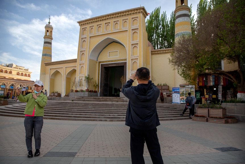 Visitors pose for photos outside a mosque in Xinjiang