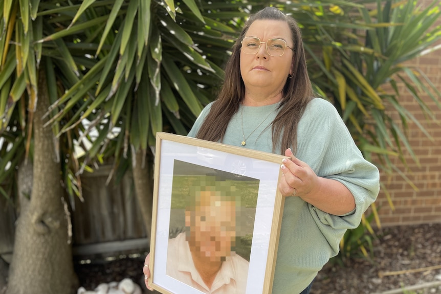 A woman holding the pixelated portrait of a man.