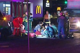 Emergency crews work on a road in front of a McDonald's restaurant