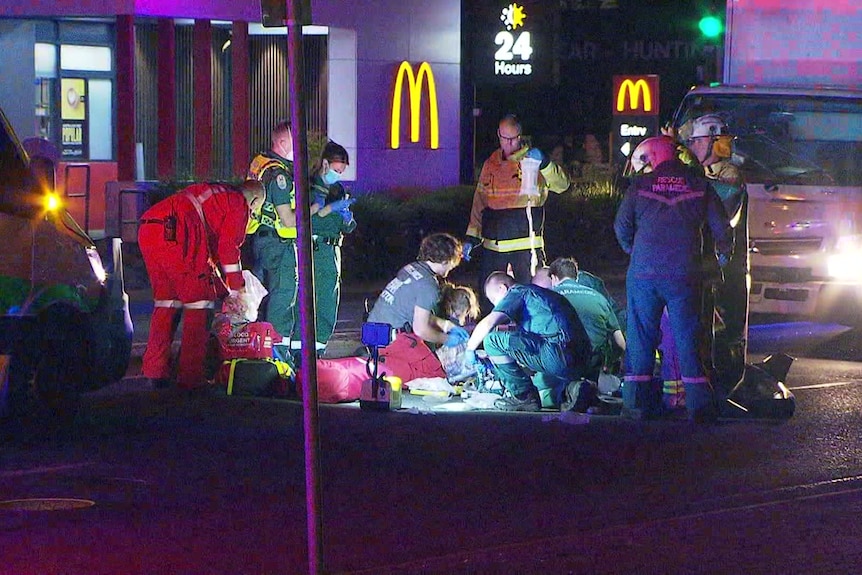 Emergency crews work on a road in front of a McDonald's restaurant