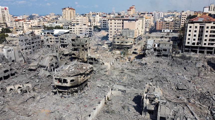 The ruins of houses and buildings sit among the grey rubble of other destroyed buildings.