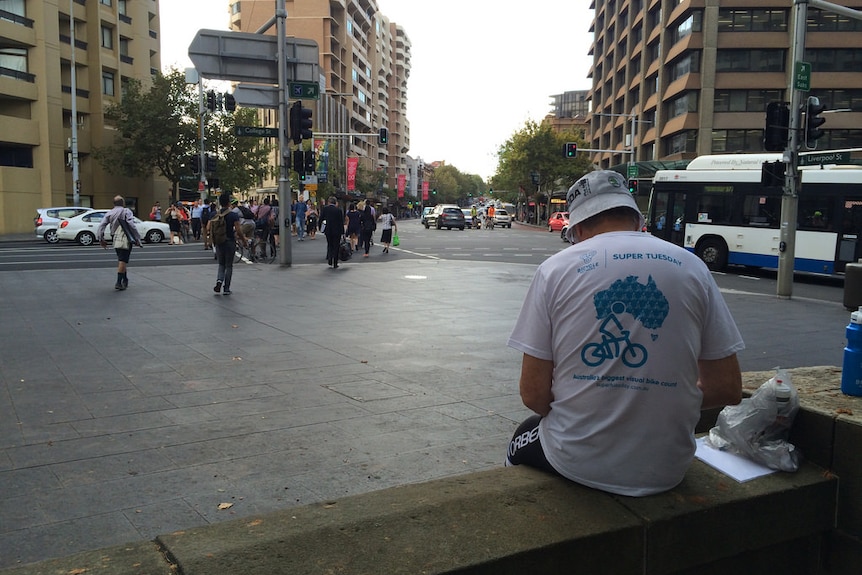 A man sits, keeping tally of passing cyclists.