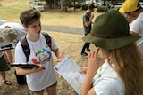 A person wearing a Yes equality t-shirt speaks to someone holding a piece of paper that says conversation guide