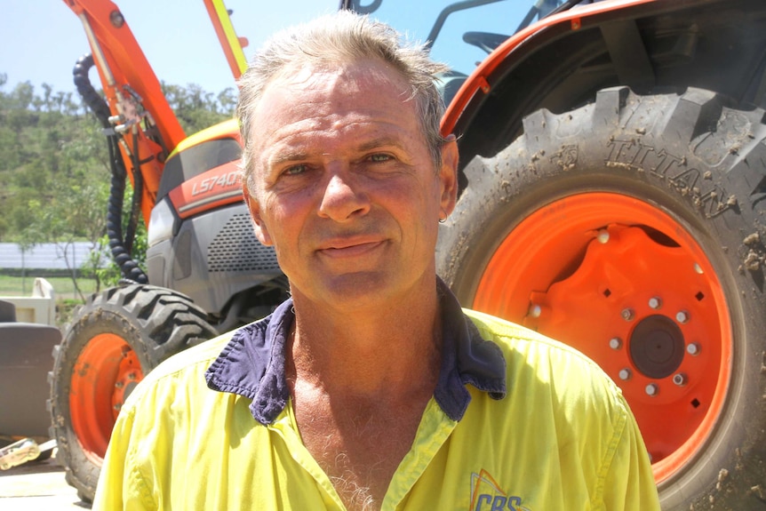 Barry Collett stands in front of a tractor.