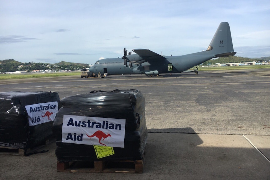 Crates of Australian aid are seen on tarmac next to an Australian Air Force plane.