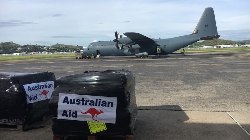 Creates of Australian aid are seen on tarmac next to an Australian Air Force plane.