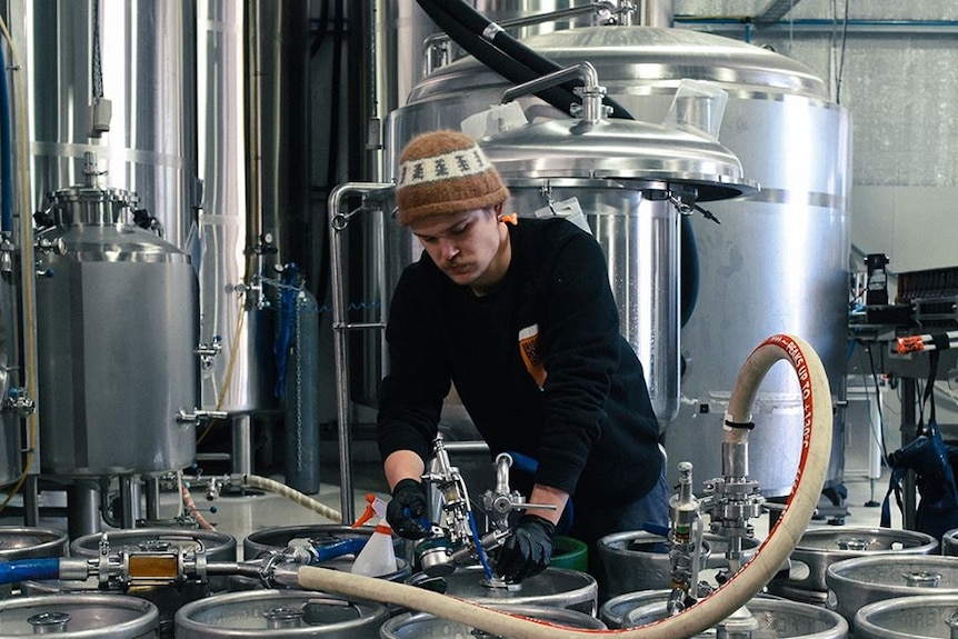 A man fills kegs in a brewery.