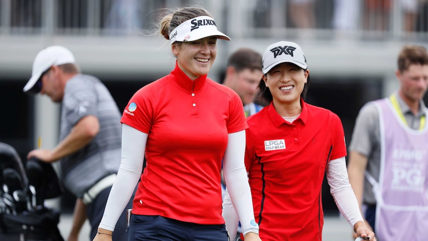 Two women golfers walk off the 18th green smiling at the Women's PGA Championship.