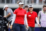 Two women golfers walk off the 18th green smiling at the Women's PGA Championship.