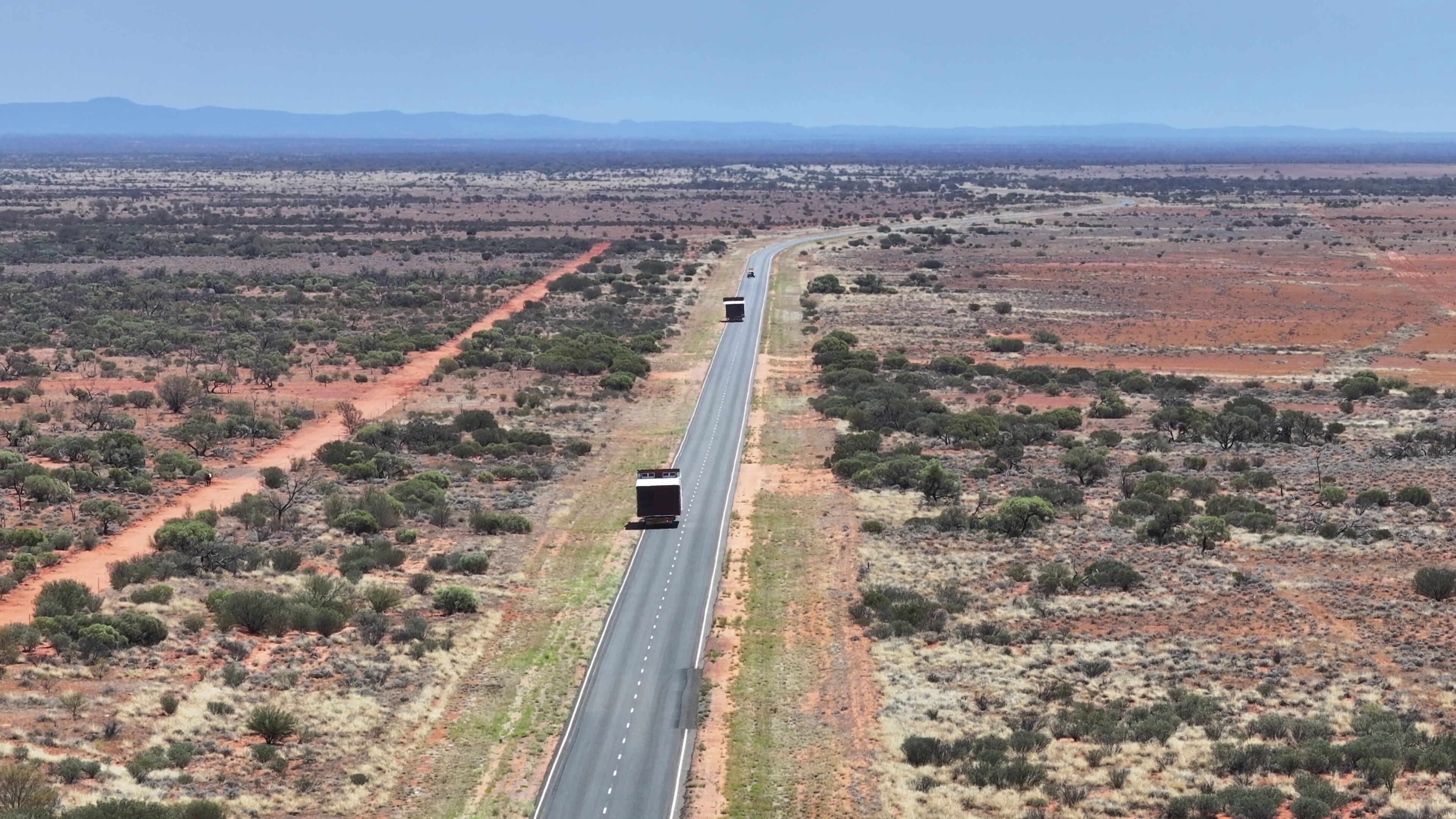 Los camiones circulan por una carretera del interior del país transportando piezas de una casa modular.