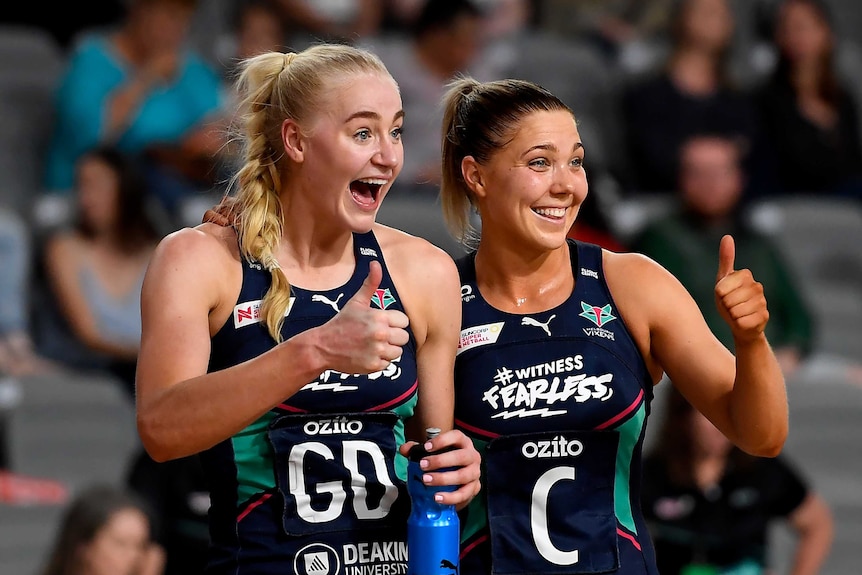 Two Melbourne Vixens Super Netball players give the thumbs up as they smile after beating NSW Swifts.
