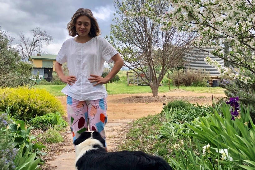 A girl looking at a black and white dog 