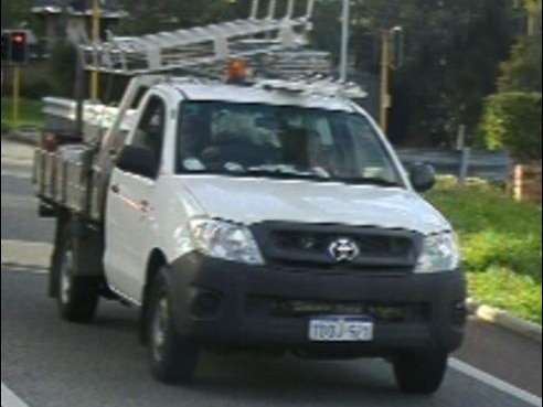 A poor quality image of a white Toyota Hilux driving on a road.