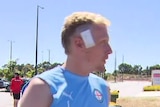 A blonde man with a bandage on his head.