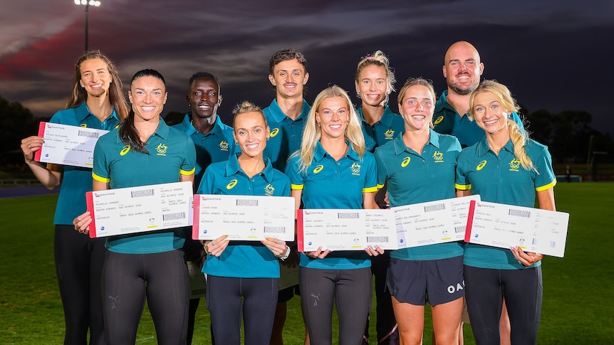 Ten athletes pose for a photo holding oversized plane tickets and wearing Australian Olympic polos