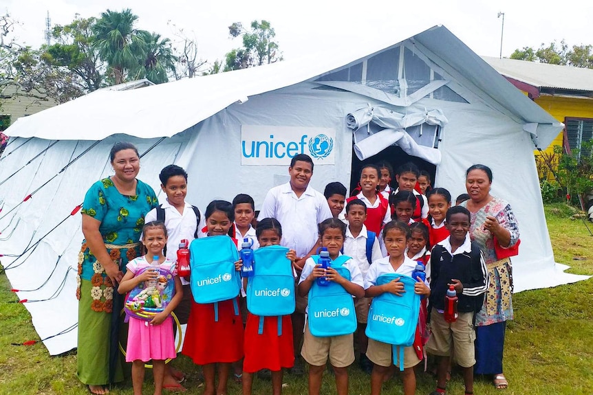 School children and teachers stand outside a make-shift tent school