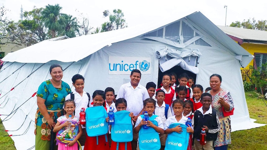 School children and teachers stand outside a make-shift tent school