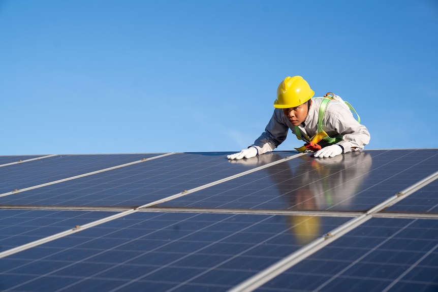 A man in a hard hat inspecting solar panels