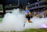 A Western Force rugby union player runs out onto the pitch, surrounded by dry ice with a home crowd in the stand behind.