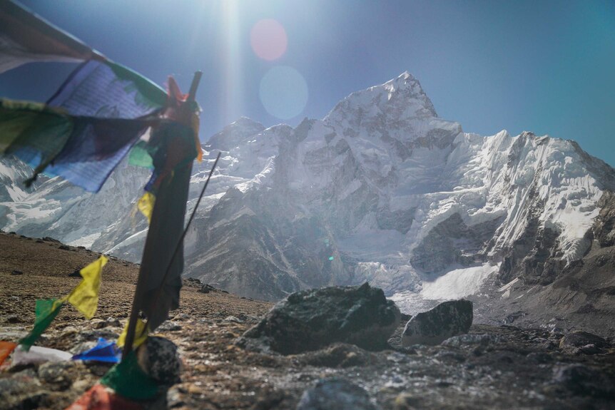 A snowy peak in the background with Tibetan prayer flags fluttering in the foreground