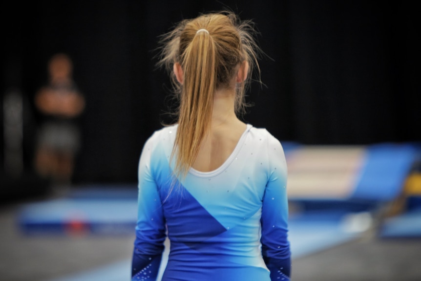 Young gymnast with her hair tied up, from behind. 
