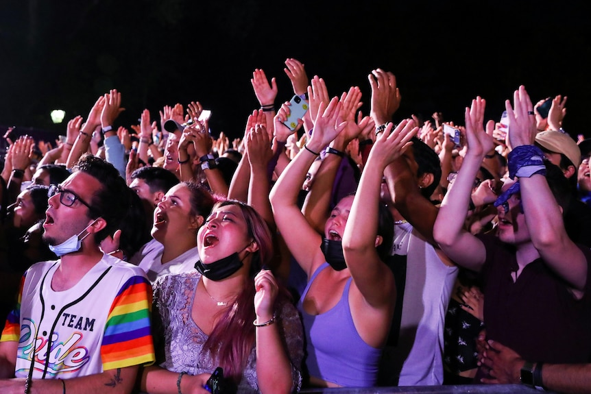 members of the crowd at Global Citizen Live in New York hold their arms in the air and sing