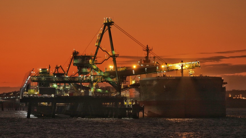 A coal load loads coal onto a large ship 