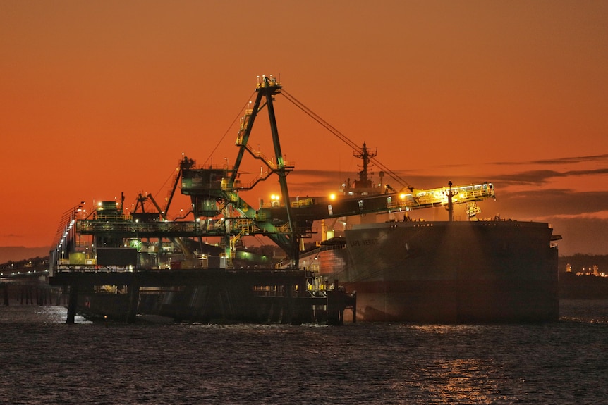 A coal load loads coal onto a large ship 