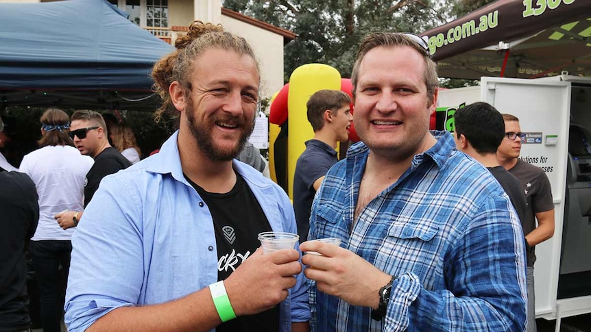 Two men smiling and holding beers.